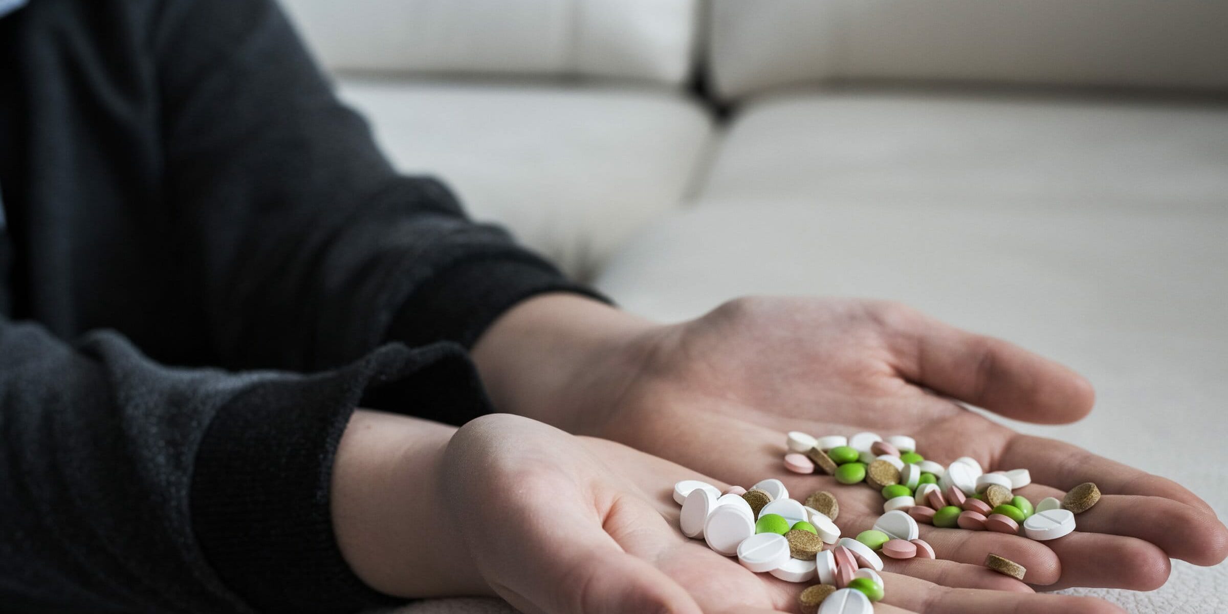 A hand holding out various pills